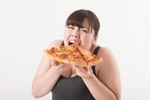 塩分の高いピザをほおばる女性の画像